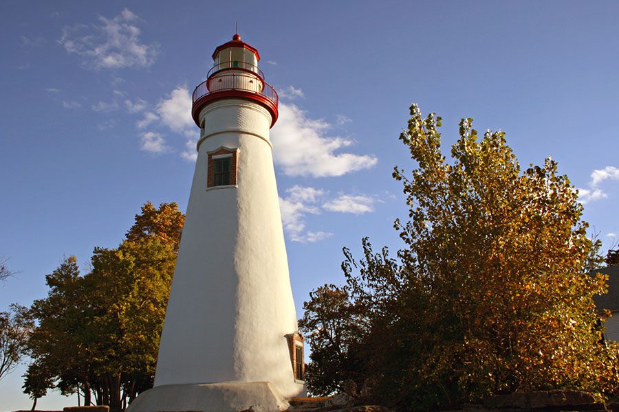 Sandusky, OH - Scenic View of a Lighthouse Surrounded by Fall Trees Against a Clear Blue Sky in Sandusky Ohio