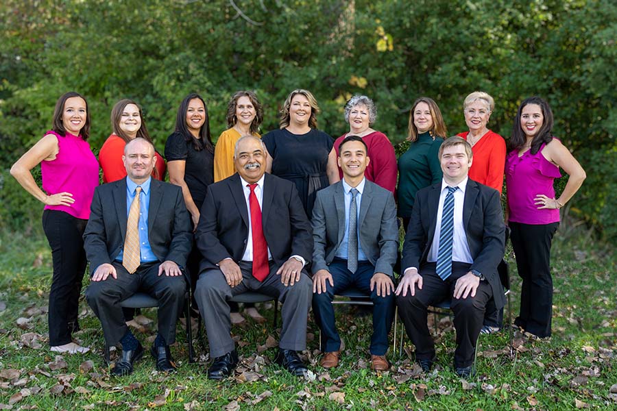 About Our Agency - Portrait of Smiling Cobos Insurance Center Team Members Outside on a Sunny Day Surrounded by Green Foliage